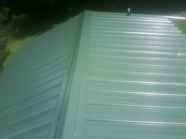 New green metal panels meeting at the ridge of a roof — Flat Roof Repair work by our crew in El Paso