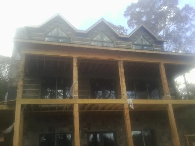 Dormers and porch framing on a large log home under construction — Roof Coating work by our crew in El Paso