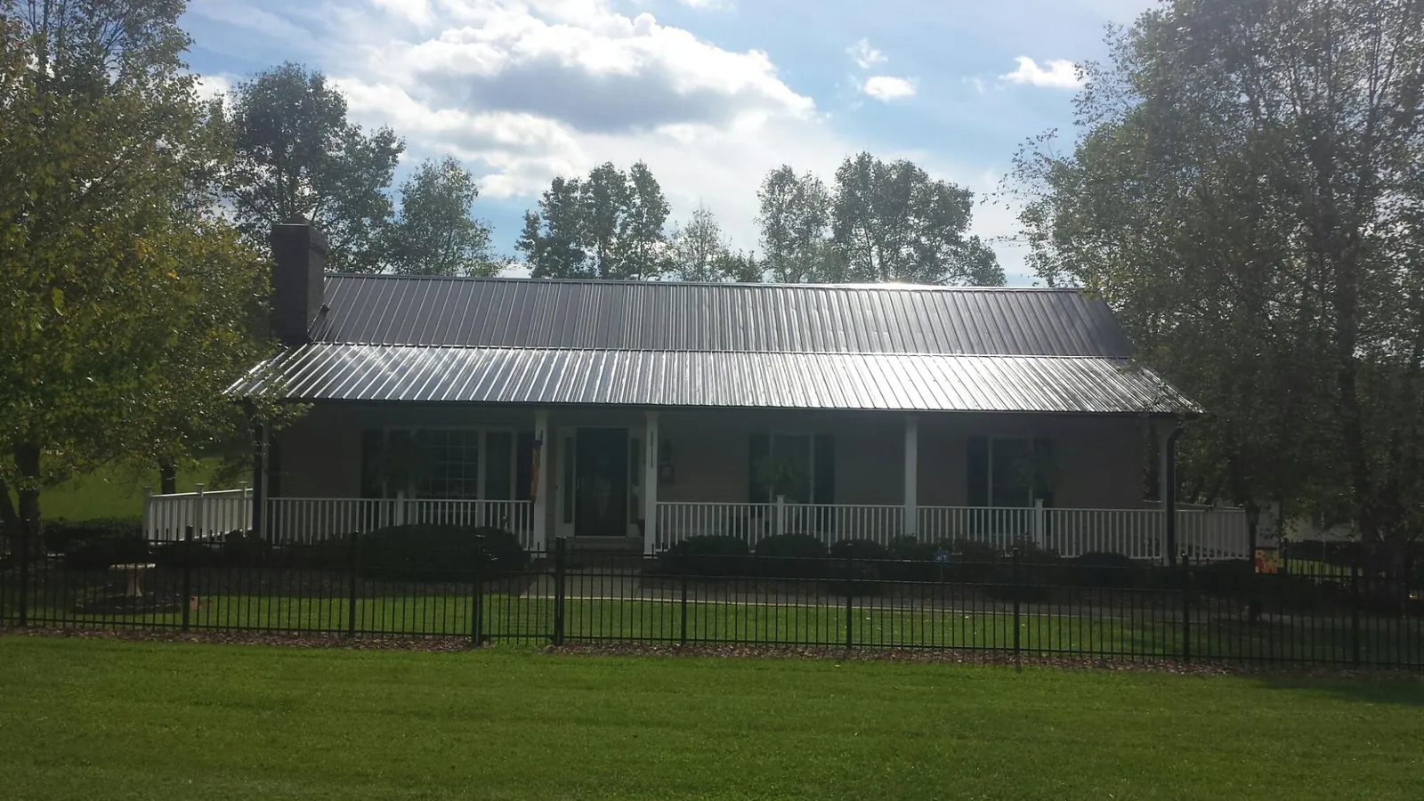 Gray metal roof on a brick ranch with a full width front porch — Gutter Guard Installation work by our crew in El Paso