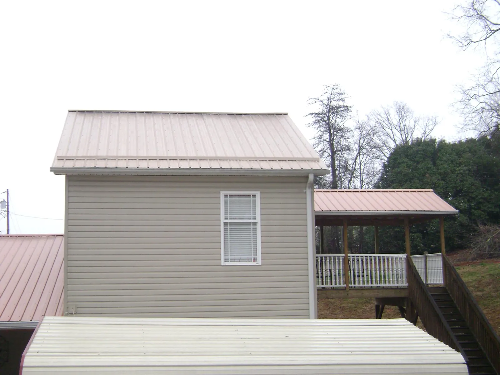 Tan metal roofs on a two story addition and attached porch, from a Roof Replacement job in El Paso
